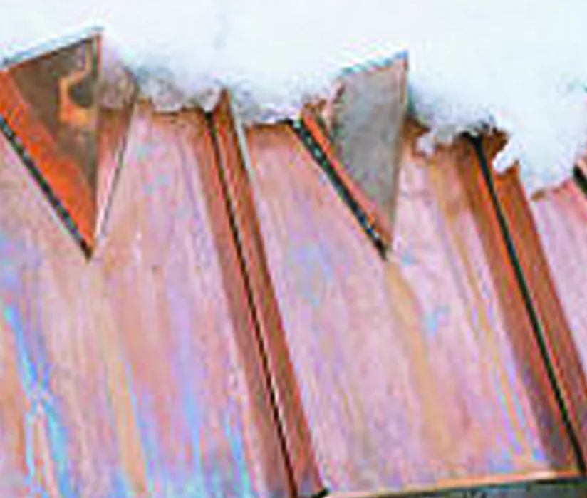 Triangular copper snow guards holding back snow on a copper standing-seam roof