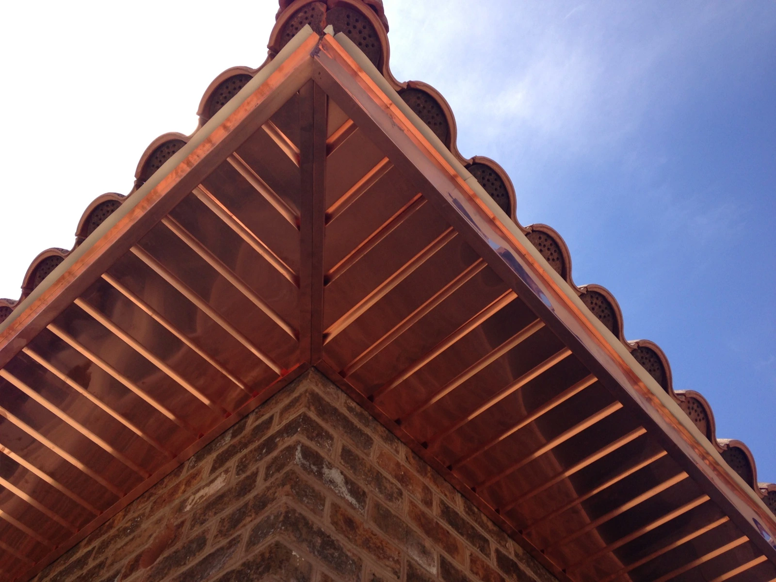 Copper slatted soffit under the eave of a tile roof