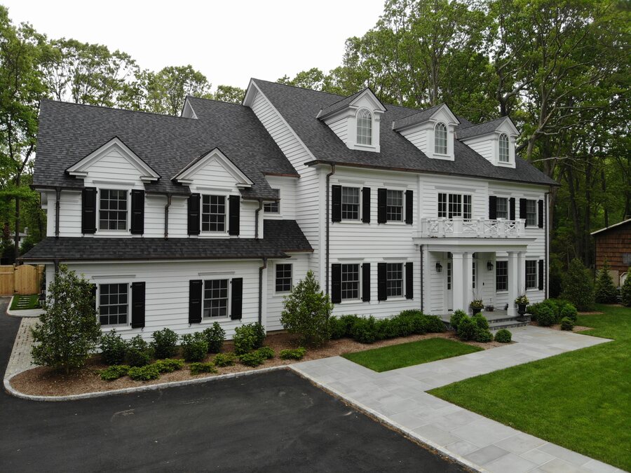 White clapboard house with black shutters, a dark shingle roof, and copper-colored gutters and downspouts