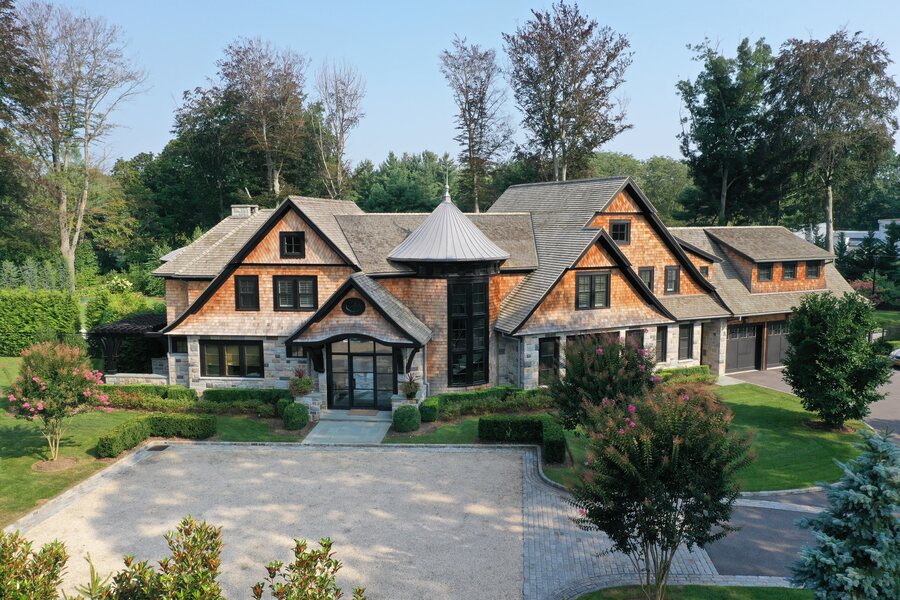 Cedar-shingle and stone house with a conical turret roof and a gravel courtyard